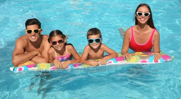 Famiglia felice in piscina, in attesa dello stipendio 15 agosto. Sorrisi e occhiali da sole per tutti!
