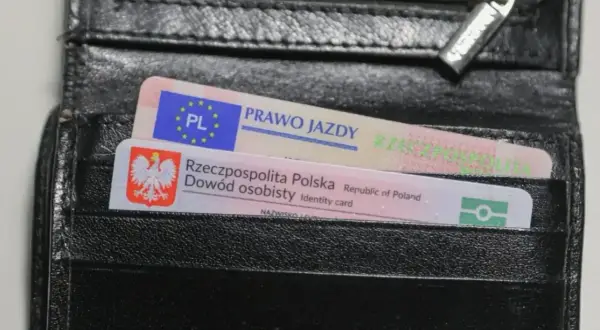 Czarny portfel z polskim dowodem osobistym i prawem jazdy. Na dokumencie prawa jazdy widnieje napis "prawo jazdy" oraz symbol UE. Na dowodzie osobistym widnieje godło Polski i napis "Rzeczpospolita Polska". Prawo jazdy ograniczenia 71.