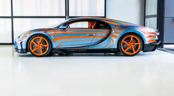 Niebiesko-pomarańczowy Bugatti Chiron Super Sport z dynamicznym wzorem falistych linii i pomarańczowymi felgami.
