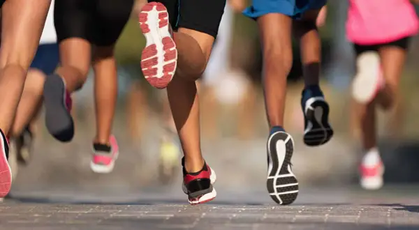 Des coureurs en action, leurs jambes et chaussures en mouvement. Une scène dynamique pour apprendre à courir.