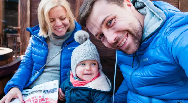Rodzina zwiedza Lwów na Ukrainie. Uśmiechnięci rodzice i dziecko z mapą.