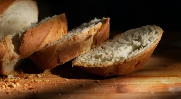 Kromki białego chleba na desce. Zastanawiasz się, ile kcal ma kromka chleba białego? Oto ona, gotowa do spożycia.