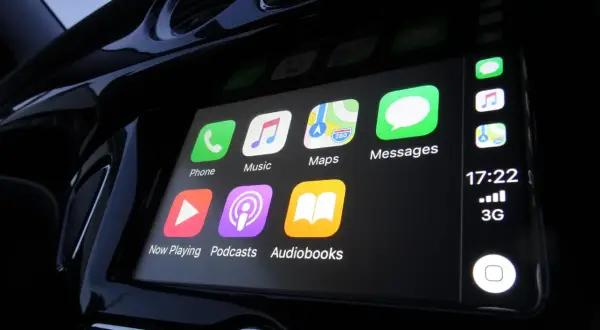 Ekran samochodu z ikonami Apple CarPlay: Telefon, Muzyka, Mapy, Wiadomości, Teraz odtwarzane, Podcasty, Audiobooki.