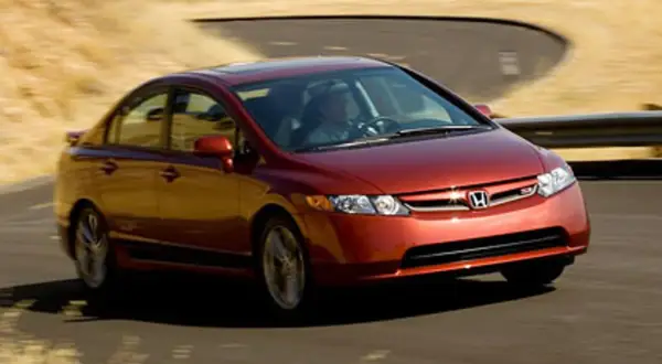 Czerwony Honda Civic Si zgrabnie pokonuje zakręt na pustynnej drodze.