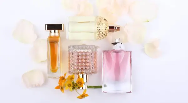 Eleganckie flakony perfum, w tym te z nutami feromonów damskich, otoczone płatkami kwiatów.