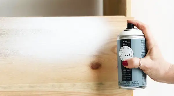 Mano spruzza primer legno per preparare la superficie prima della verniciatura. Utile per uniformare e far aderire meglio il colore.