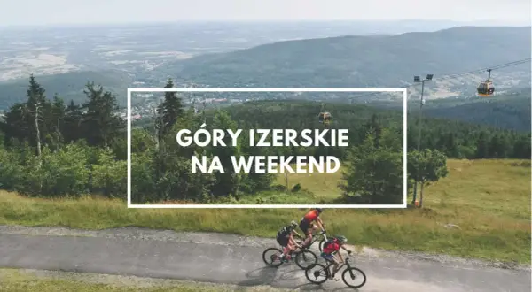 Trzech rowerzystów przemierza malownicze szlaki w Górach Izerskich w Polsce. W tle widać kolejkę gondolową i rozległy krajobraz.