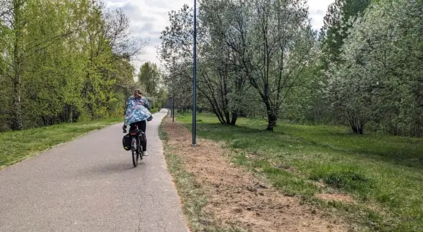 Osoba na rowerze jedzie ścieżką wzdłuż zielonego parku. To piękna pogoria 3 trasa, idealna na wiosenną przejażdżkę.