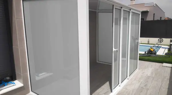 Moderno cierre para balcones y terrazas con puertas correderas de cristal y panel opaco.