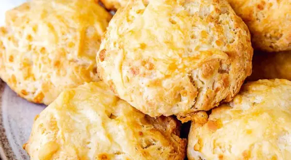 En hög med gyllene, fluffiga ostscones, perfekta för en mysig fika.
