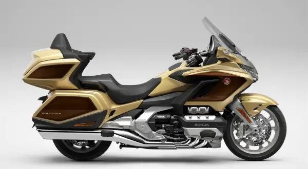 Złoty Honda Goldwing, luksusowy motocykl turystyczny z brązowymi akcentami, gotowy na dalekie podróże.
