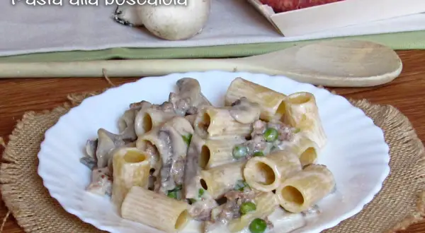 Piatto di pasta alla boscaiola con funghi, piselli e salsiccia, servita su un piatto bianco con un tovagliolo di juta.