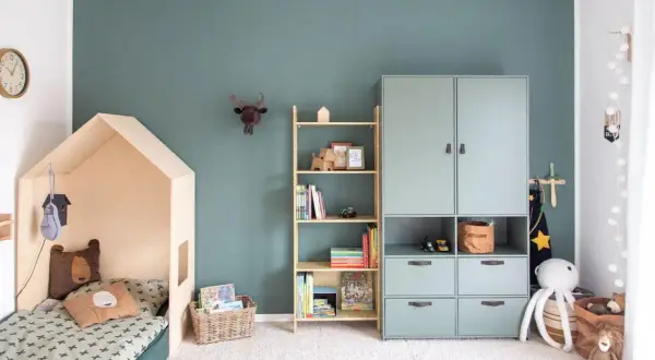 Gemütliches Kinderzimmer für Grundschulkinder mit Hausbett, Bücherregal und Spielzeug.