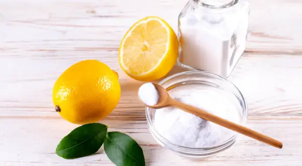 Limoni, bicarbonato e una ciotola con la struttura dell'acido citrico, pronti per un rimedio naturale.