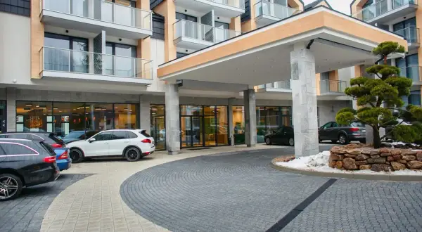 Nowoczesny hotel z parkingiem i drzewkiem bonsai.
