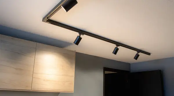 Svart spotlightskena med flera justerbara lampor ger modern belysning hall inspiration. Ljuset träffar ljusa träskåp.