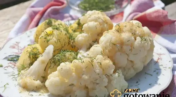 Gotowany kalafior i ziemniaki polane sosem, posypane koperkiem. Idealna zasmażka do kalafiora sprawia, że danie jest pyszne.