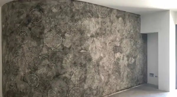 Parete curva con un suggestivo intonaco a calce decorato con motivi floreali e geometrici in stile damascato.