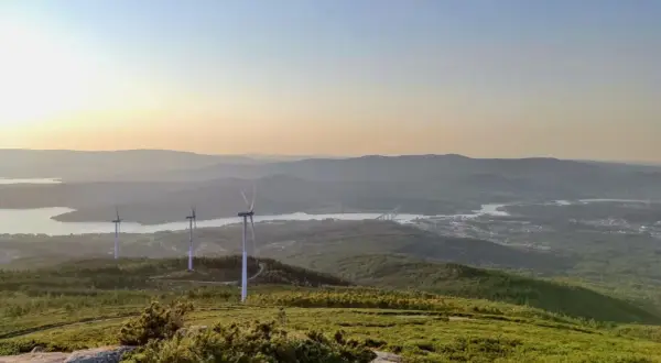 Vistas del monte Xiabre con molinos de viento y un río al atardecer.