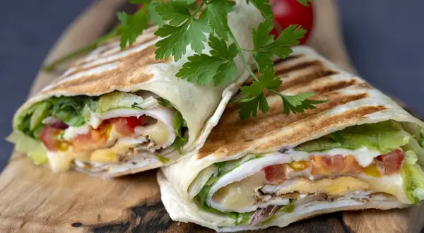 Pyszna tortilla z jajkiem, serem, warzywami i kurczakiem, podana na desce.