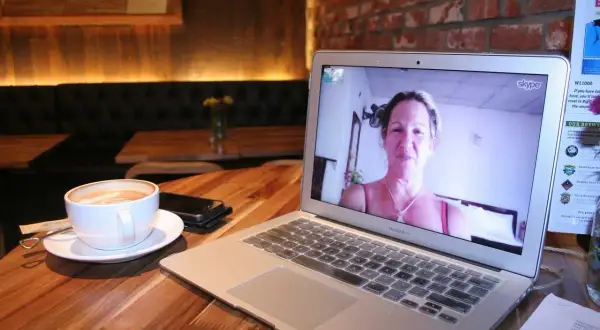 Kawa i laptop z rozmową przez Skype. Dowiedz się, jak zainstalować Skype na komputerze, by połączyć się z bliskimi.
