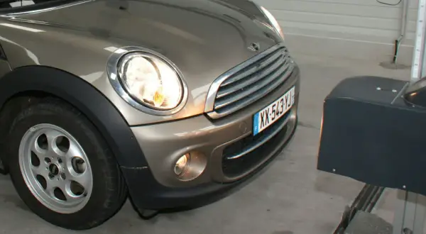 Réglage des feux diurnes d'une Mini Cooper marron, avec un appareil de mesure à droite.