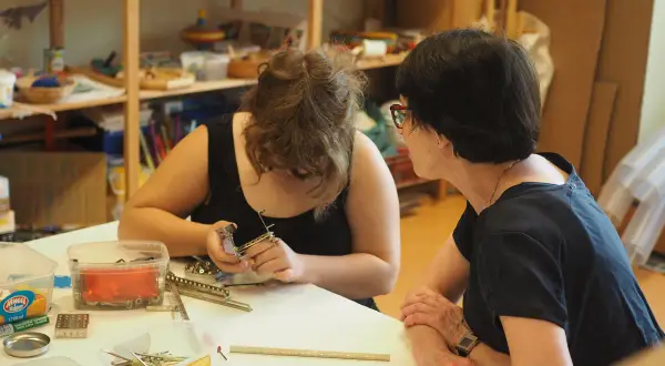 Zwei Frauen arbeiten in einer Lernwerkstatt im Kindergarten. Eine baut mit kleinen Metallteilen.