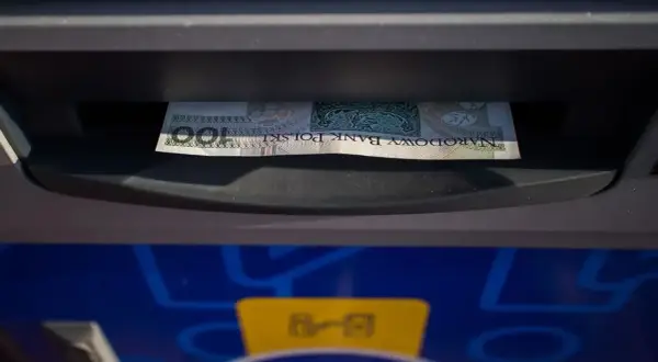 Jednorazowa wpłata gotówki do bankomatu. Banknot 100 zł wchodzi do szczeliny.
