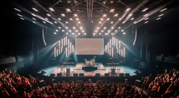 An empty concert stage with drums and keyboards awaits the band. The audience is seated, ready for the show to begin, and wondering what is the average length of a concert.
