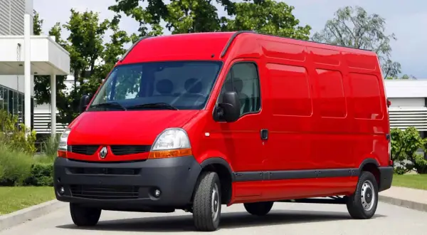 Czerwony Renault Master 2, gotowy do pracy, stoi na tle zieleni i nowoczesnego budynku.