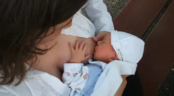 Mama karmi piersią dziecko. Czas karmienia jest indywidualny, ale ważne, by maluch był najedzony.