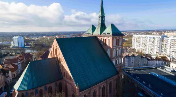 Imponująca katedra góruje nad panoramą jednego z miast w zachodniopomorskim. W tle widać blokowiska i inne budynki.