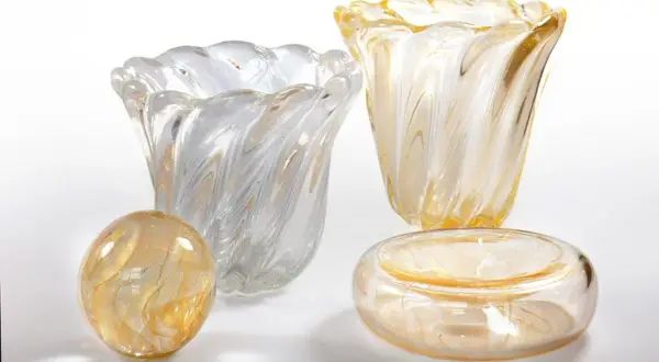 Vasi e oggetti decorativi in vetro soffiato, con fili dorati e bianchi, che evocano la maestria di Seguso Vetri d'Arte.