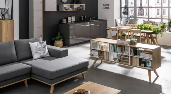 Nowoczesny salon z szarą kanapą i ciemną ścianą. Inspiracje na kolory ścian do salonu: grafit, biel, drewno.