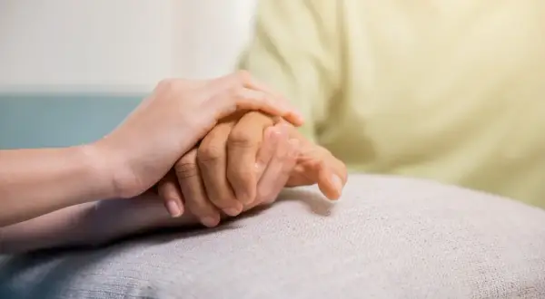 Zwei Hände halten sich fest. Eine jüngere Hand stützt eine ältere, was Hoffnung und Unterstützung für COPD Pflegegrad symbolisiert.