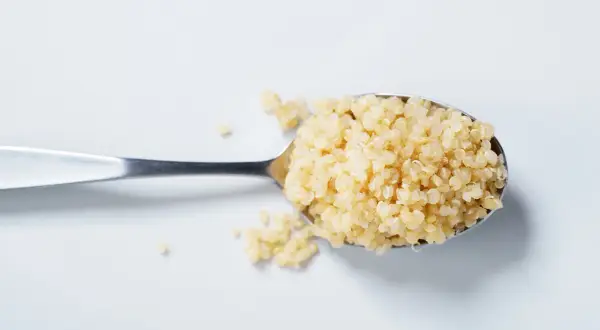 Ein Löffel voll gekochter Quinoa, bereit für eine gesunde Mahlzeit.