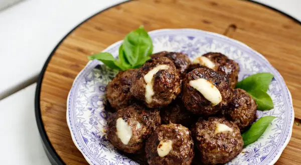 Köttbullar med ost, ett gott recept för viktnedgång gratis. Serveras på en vacker blåvit tallrik med basilika.