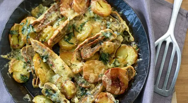 Herzhafte Maultaschen-Pfanne mit goldbraunen Kartoffelscheiben und geschmolzenem Käse, garniert mit frischen Kräutern.