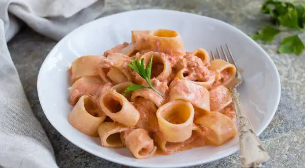 Un piatto di pasta al tonno cremosa, con paccheri conditi e guarniti con prezzemolo fresco.