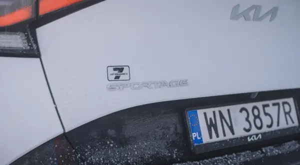 Białe Kia Sportage z polską tablicą rejestracyjną WN 3857R. Widoczny znaczek 7 lat gwarancji.