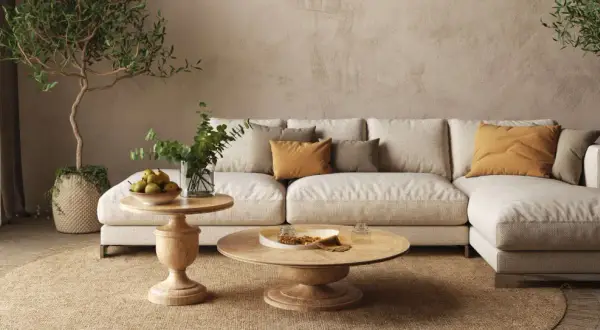 Accogliente salotto con divano chiaro, cuscini ocra e verdi, tavolini in legno e piante. Un'atmosfera rilassante con salotto colori caldi.