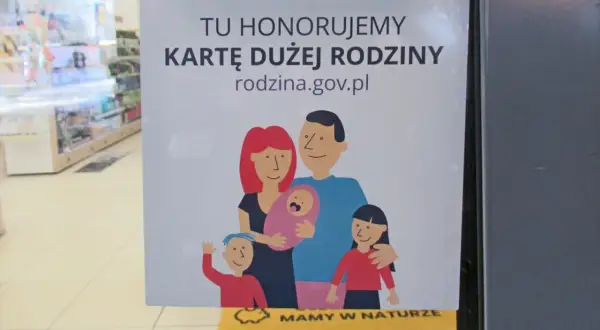 Plakat informuje, że honorowana jest karta dużej rodziny. Widnieje na nim rysunek rodziny z dwójką dzieci i niemowlęciem.