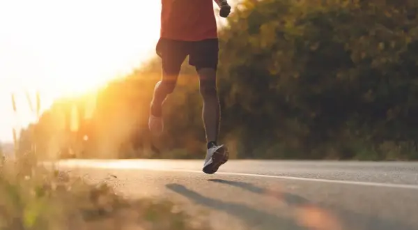 Läufer auf einer Straße im Sonnenuntergang, intensive **Vorbereitung Halbmarathon**.