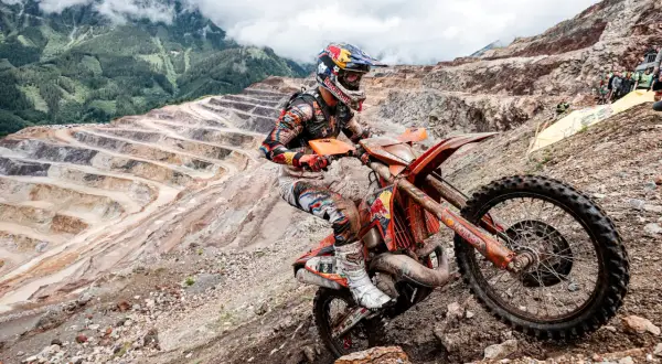 Motocyklista hard enduro na pomarańczowym motocyklu w kopalni odkrywkowej.