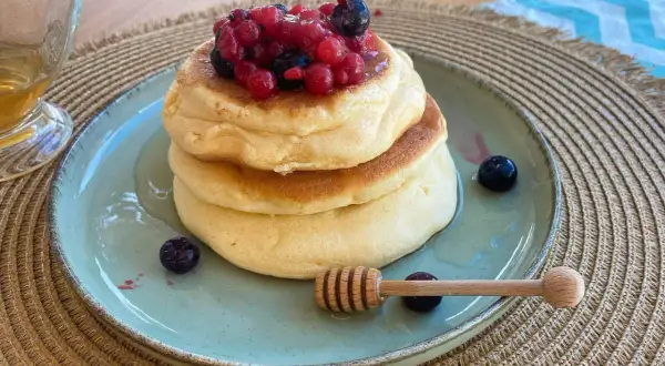 Pancake senza zucchero soffici e dorati, guarniti con frutti di bosco freschi e miele. Un dolce sano e delizioso.