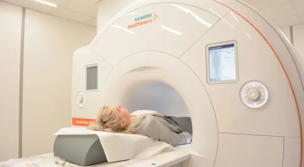 Kobieta leży w aparacie do rezonansu magnetycznego, przygotowując się do badania miednicy.
