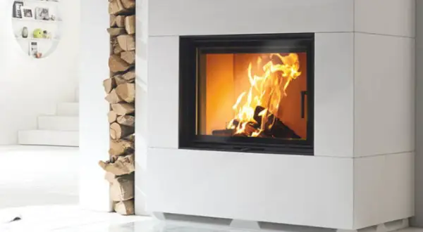 Moderner Kamin mit brennendem Feuer. Holzstapel daneben. Unterschied zwischen Zeitbrand und Dauerbrand ist hier nicht ersichtlich.