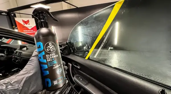 Rękawica z preparatem SWAG Glass Cleaner Gel pokazuje, czym umyć szyby w samochodzie. Żółta taśma na szybie wyznacza obszar czyszczenia.
