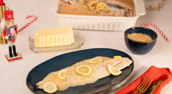 Un bar en croûte de sel, tel que préparé par Julie, est servi avec des rondelles de citron. Un beurre crémeux et une sauce à la moutarde complètent ce plat festif.
