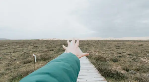 Ręka wyciągnięta w kierunku ścieżki przez pusty krajobraz, symbolizująca **widzenie tunelowe psychologia** i dążenie do celu.